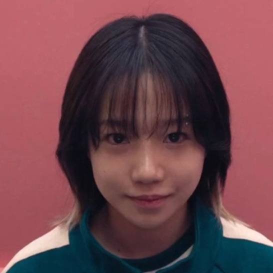 jo yuri squid game 2 salarywoman-bangs-pinkbackground-greenjacket.